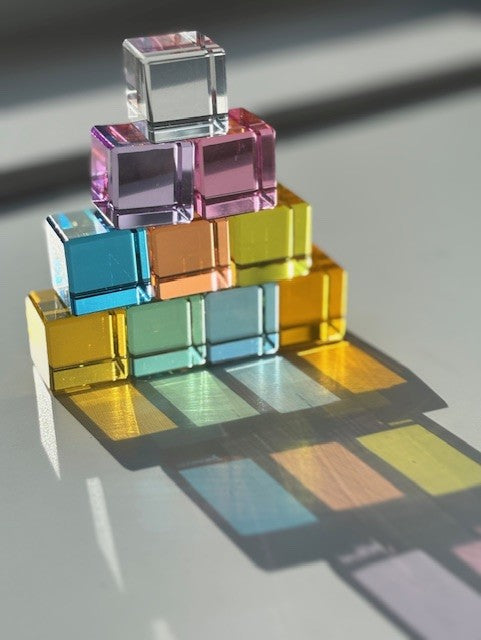 Stack of colorful transparent cubes on a reflective surface