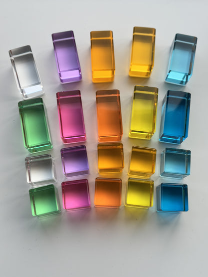 Rectangle and Cube Square Acrylic Pastel Coloured Building Blocks for Children laid out in a stacked flat lay pattern; cube, cube, rectangle, rectangle. Showing an array of pastel colours; pink, purple, light blue, pastel green, peach, three shades of yellow and clear.